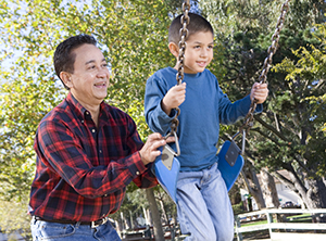 Man pushing boy on swing.