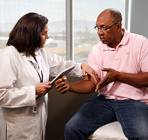 Healthcare provider talking to man in exam room.