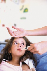 Una niña enferma con el termómetro en la boca