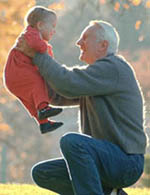 Fotografía de un abuelo levantando a su nieto mientras sonrie