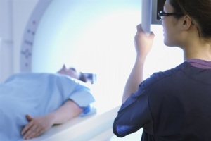 Persona en una mesa entrando en un escáner de resonancia magnética mientras el tecnólogo observa