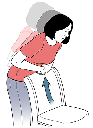 Mujer reclinada sobre el respaldo de una silla realizándose compresiones abdominales.